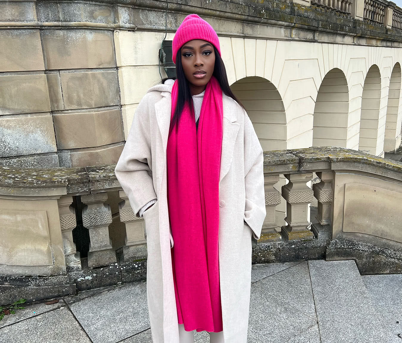 A young lady wearing a SAINTE MER cashmere scarf and hat set in Pink Lipstick